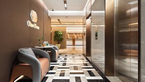 Um saguão de hotel moderno com balcão de recepção, área de estar e elevador.
