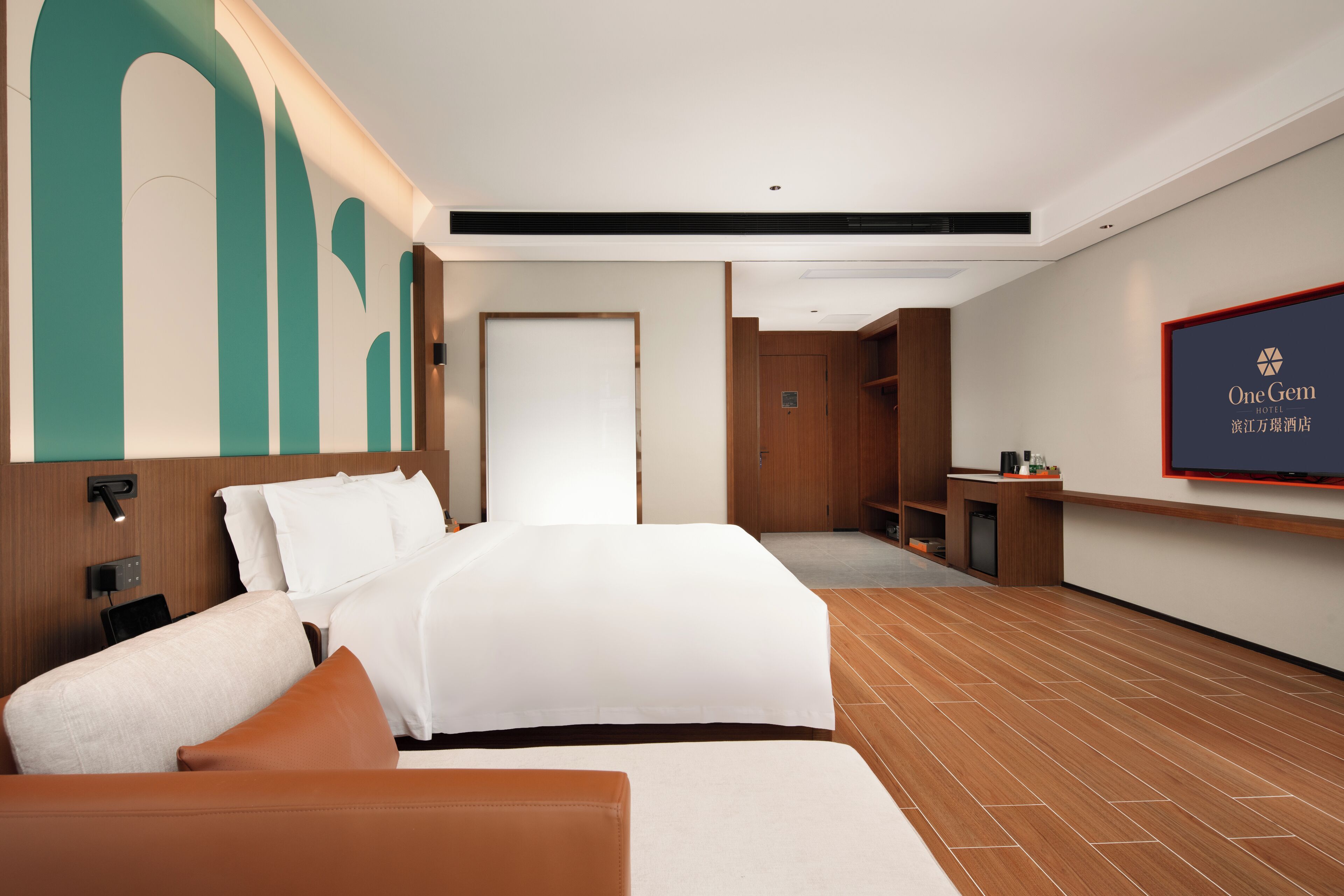 A hotel room with a large bed, a desk, a television, and a wooden floor.