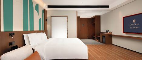 A hotel room with a large bed, a desk, a television, and a wooden floor.