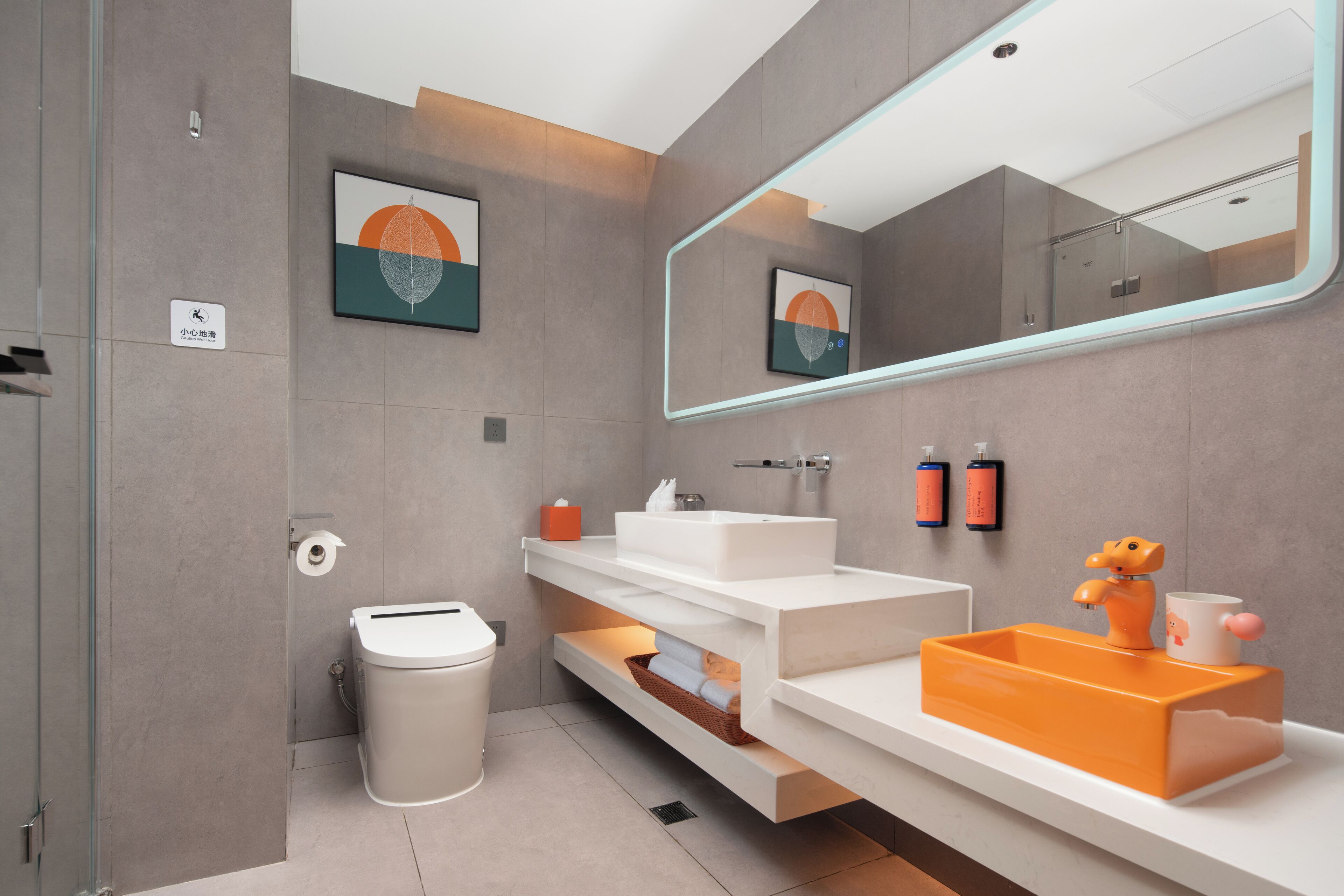 Un baño moderno con un espejo grande, un lavabo blanco y un inodoro. Hay dos botellas de jabón de manos en la pared.