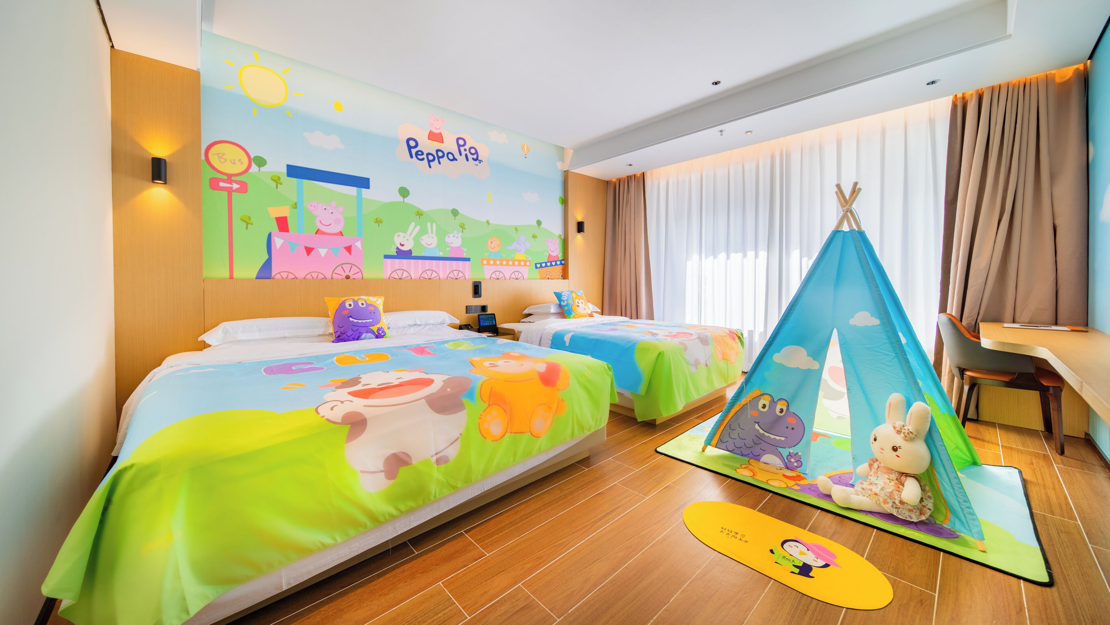 A children's room with two beds, a mural, a tent, and a desk.