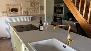 A kitchen with a large island, a built-in oven, and a wooden staircase.