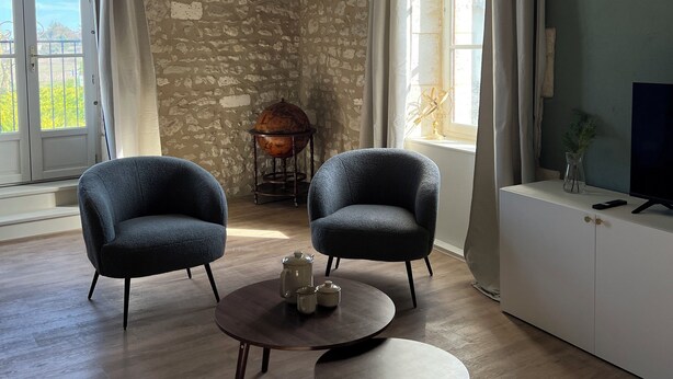 A room with two armchairs, a small coffee table, a globe on a stand, and a TV on a cabinet.