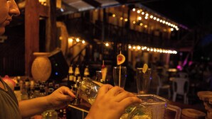 A bar setting with a person pouring a drink into a glass.