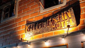 A brick building with a sign reading "KATAMARAN HOTEL" and a signboard for "KATAMARAN BAR" open to the public from 5:00 PM to 11:00 PM, offering snacks, cheese, and flavored drinks.