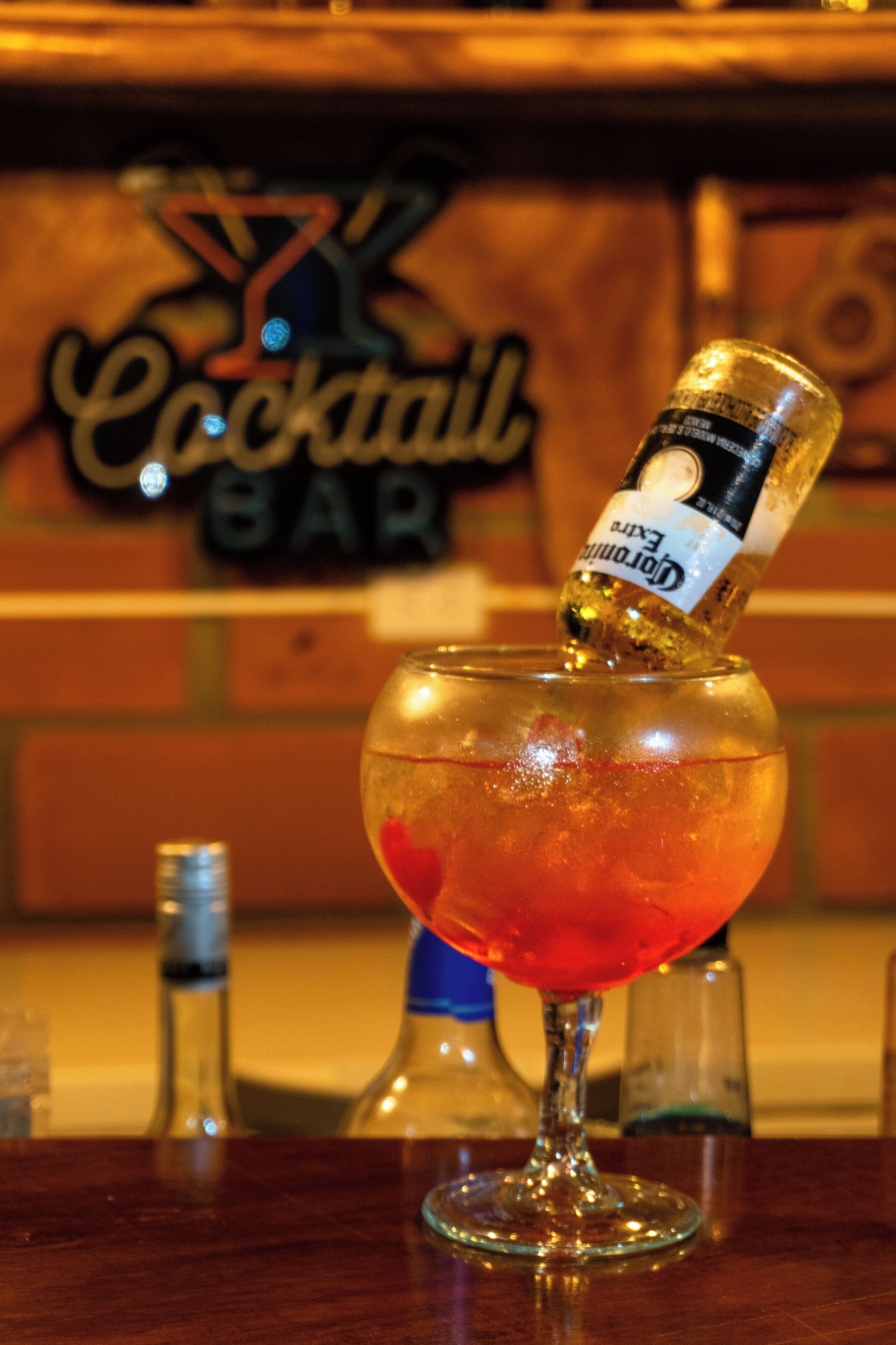 A cocktail glass with a bottle of Corona Extra beer being poured into it.