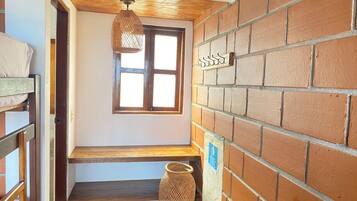 Una escalera con barandilla de madera, una cesta de mimbre y una lámpara colgante.