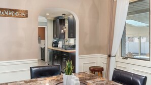 A dining area with a marble table, black leather chairs, a potted plant, and a kitchen in the background. - The Jolly Rancher (Slatington)