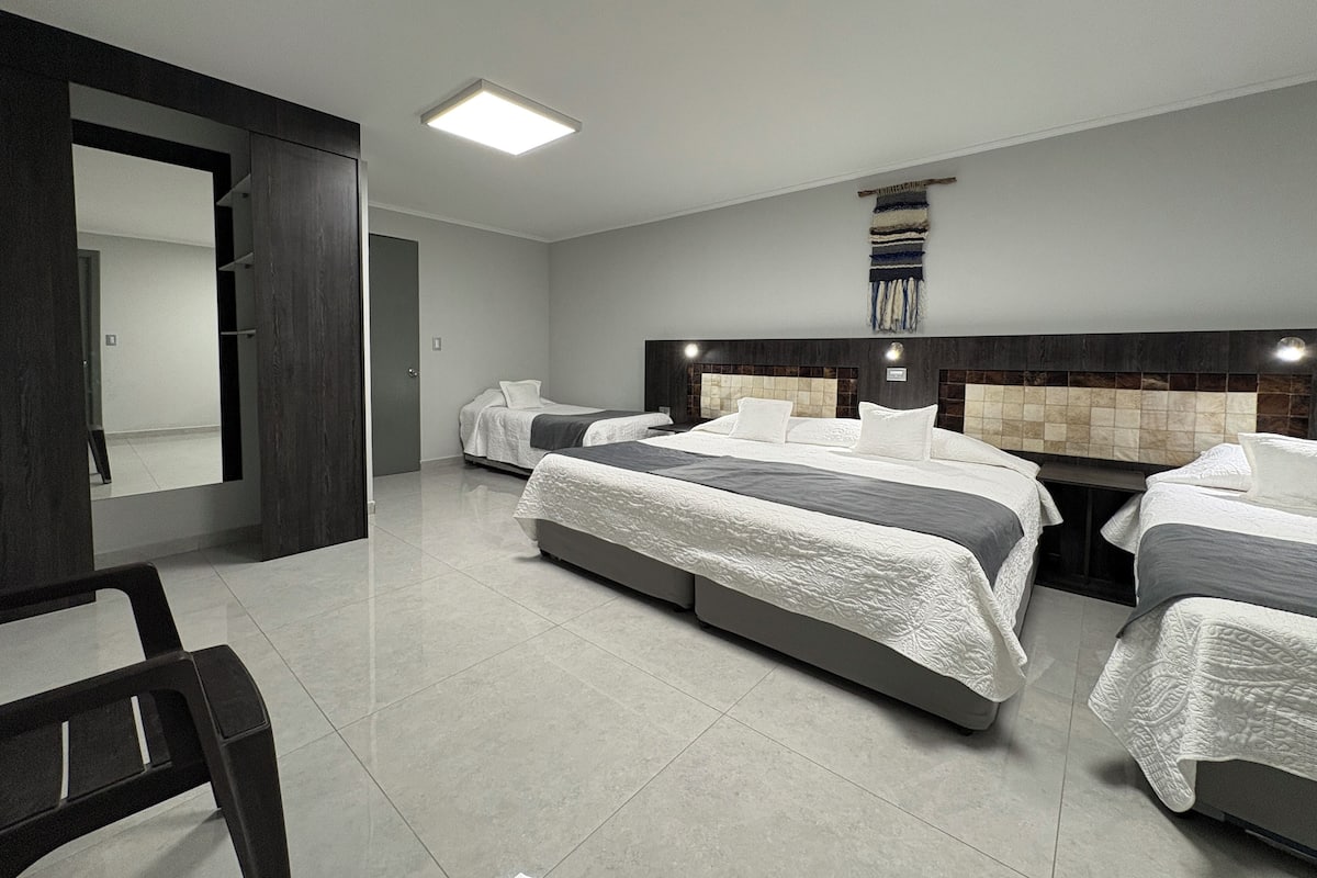 A modern hotel room with two beds, a large mirror, and a dark wood wardrobe.
