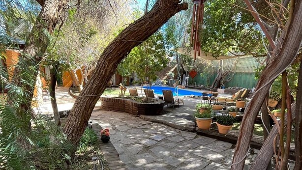 A stone patio with a pool, surrounded by potted plants and outdoor furniture. - Atankalama (Calama)