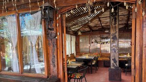 A rustic wooden interior with a brick wall, wooden ceiling beams, and a dining area with tables and chairs. - Atankalama (Calama)