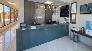 A reception area with a glass counter, a mounted television, and a water dispenser. - Atankalama (Calama)
