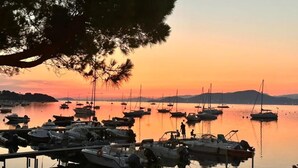 Un port de plaisance où des bateaux sont amarrés sur des eaux calmes, au coucher du soleil.