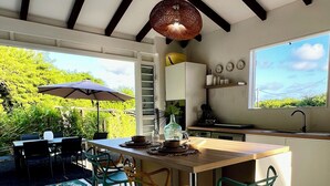 Una cucina moderna con una grande isola, un'area pranzo con sedie e vista sul verde circostante.