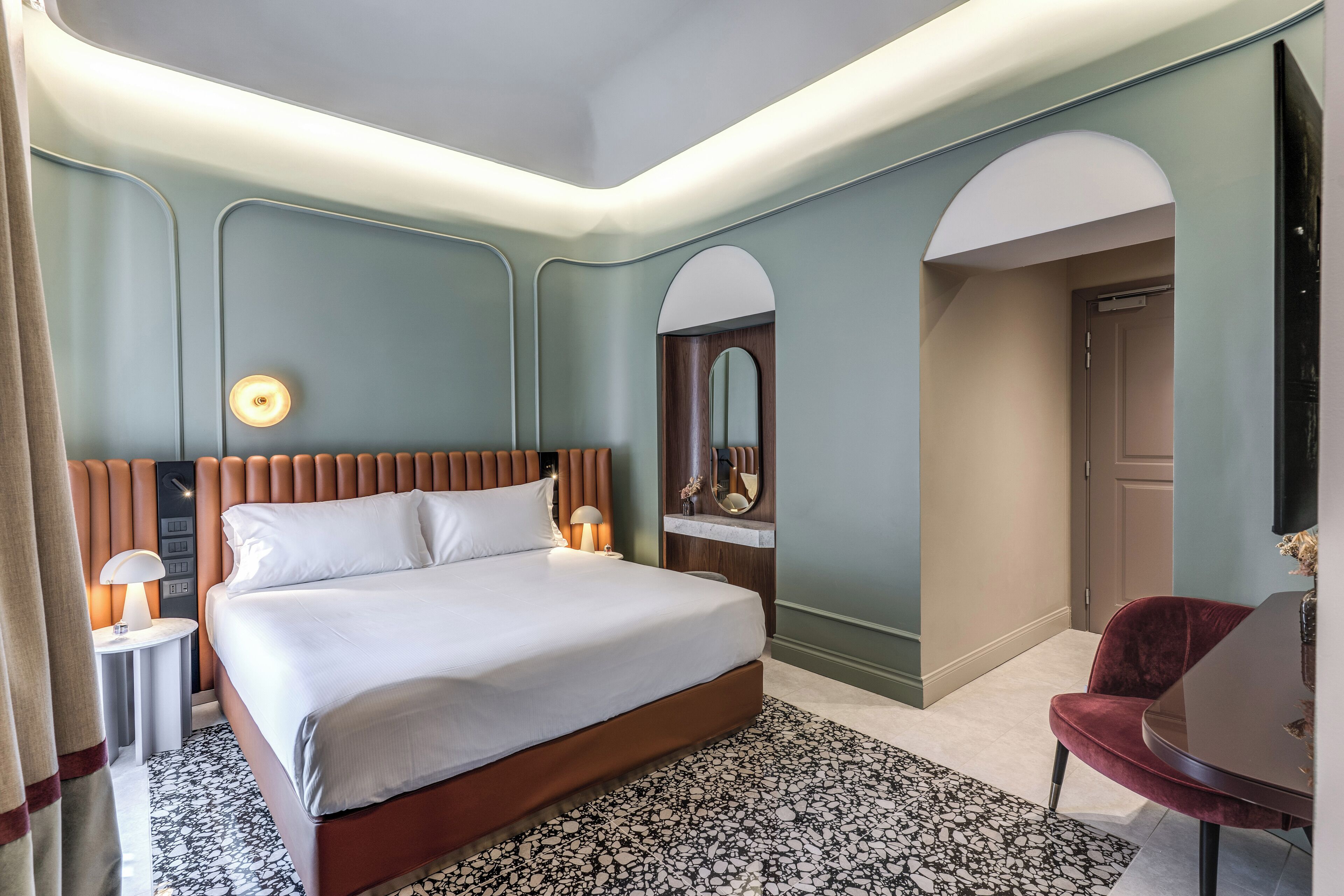 Une chambre d’hôtel moderne avec un grand lit, une table ronde et un miroir.