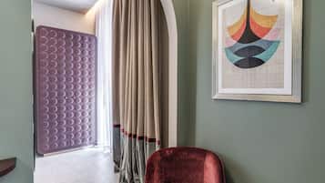 Ein Zimmer mit einer violetten strukturierten Trennwand, einem roten Samtstuhl und einem gerahmten abstrakten Kunstwerk an der Wand.