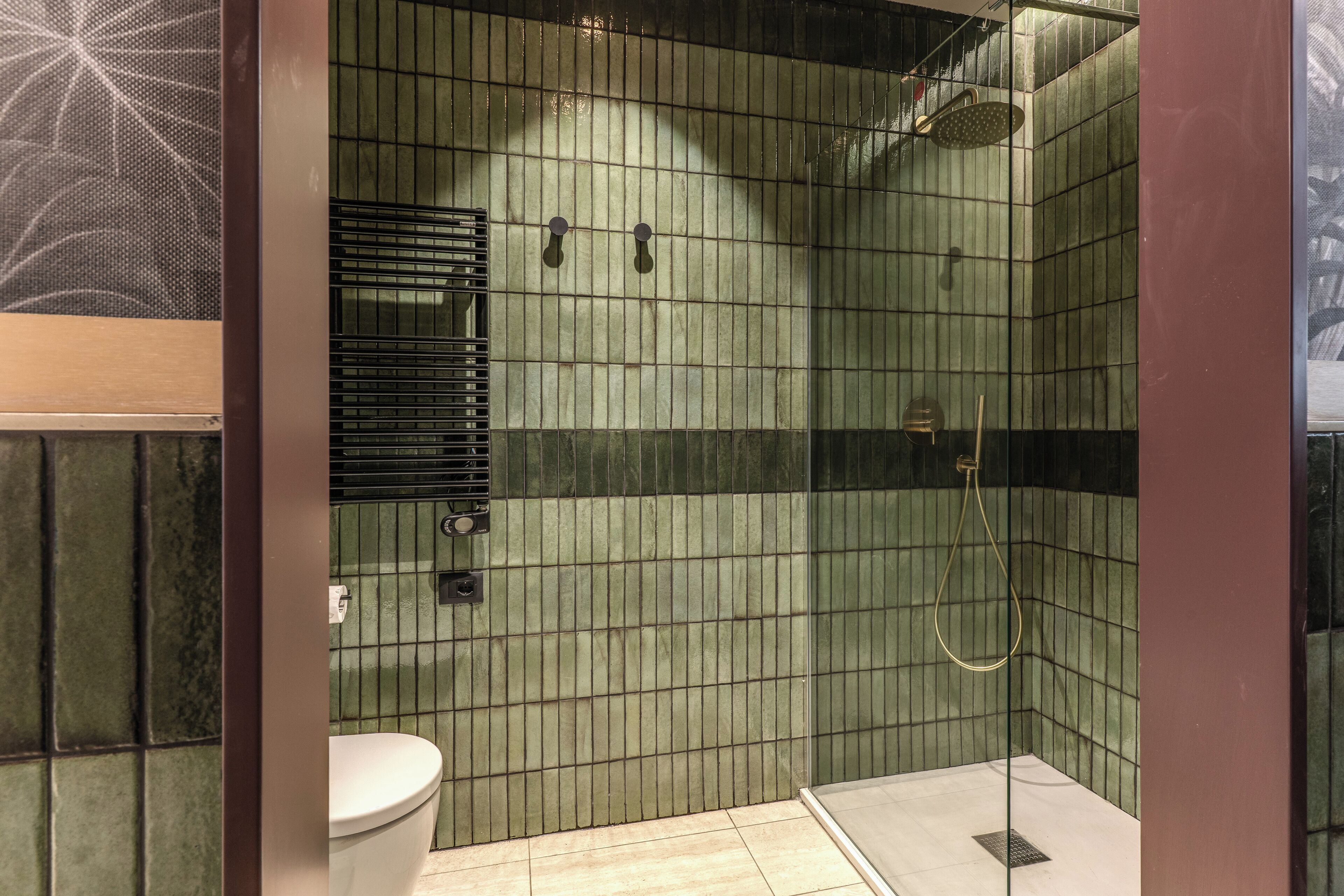 Une salle de bain avec une douche carrelée, des toilettes et un système de ventilation.