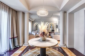 A luxurious lobby with a marble floor, a round table with a vase of dried flowers, and a chandelier. - Dimora Coppelle - Adults Only (Rome)