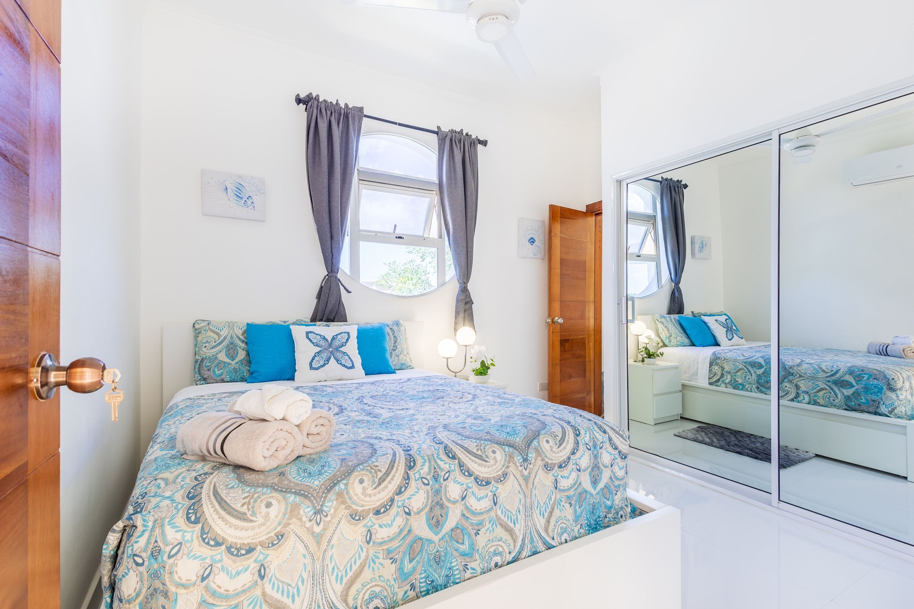 A bedroom with a bed, a nightstand, a mirror, and a wardrobe.