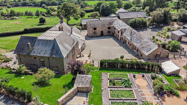 A stone building with a courtyard, surrounded by green fields and hills. - Linscott Farmhouse in Moretonhampstead (Newton Abbot)