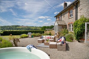 A stone house with a garden patio featuring wicker furniture and a flag.