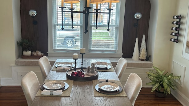 Un comedor con una mesa de madera dispuesta para seis personas, rodeada de sillas acolchadas.