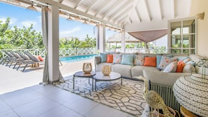 A covered outdoor seating area with a pool view, a sofa with colorful cushions, and a patterned rug. - Detached Villa with private pool within walking distance to the beach & restaurants (Jan Thiel)