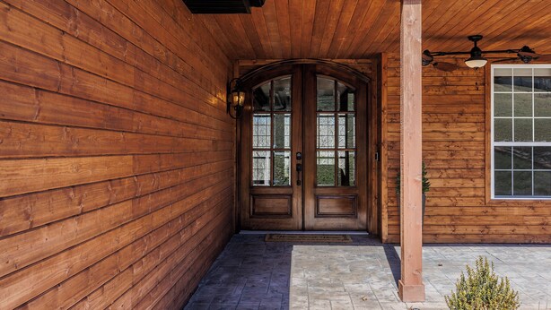 A wooden exterior with a double door and a small porch area.