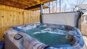 A hot tub with a control panel, surrounded by wooden deck and a covered area.