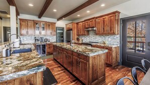 A spacious kitchen with wooden cabinets, granite countertops, and a large island.