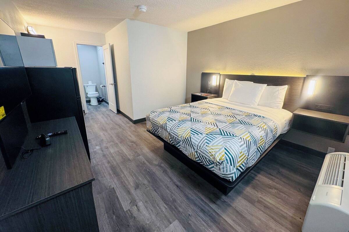 Une chambre d’hôtel comprenant un lit, des tables de chevet, un bureau, une chaise, des toilettes et une douche.