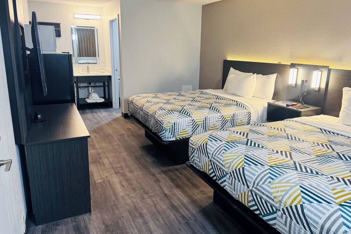 Une chambre d’hôtel avec deux lits, un bureau et un miroir.