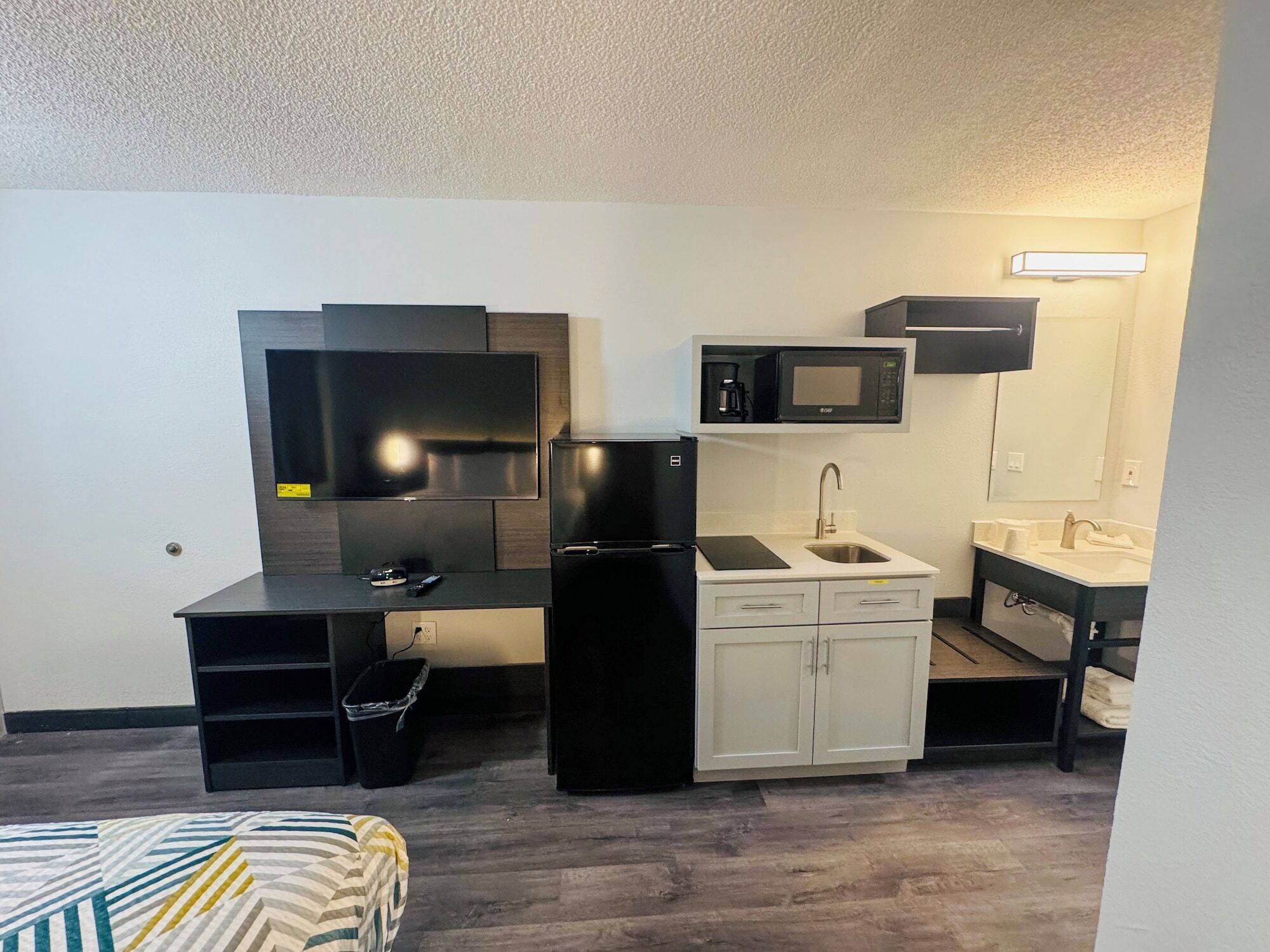 A compact kitchenette with a refrigerator, microwave, sink, and a small countertop.