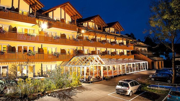 Un hotel de varios pisos con balcones, una zona de estar al aire libre cubierta y un estacionamiento.