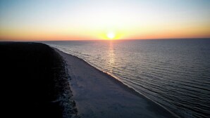A beach with a sunset, calm sea, and a path leading to the water. - Apartamenty EDEN & sauna Posesja Kapitańska Grzybowo by POSESJA APARTAMENTY (Grzybowo)