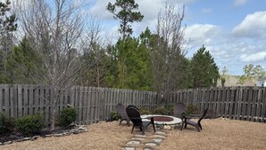 Un jardin avec un chemin de pierres menant à un espace détente comprenant deux chaises et une table.
