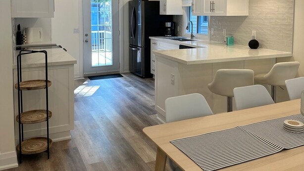 Une cuisine moderne avec des meubles blancs, un îlot central et des luminaires suspendus.