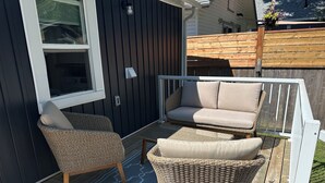 Une terrasse dotée de meubles en osier, d’un canapé moelleux et d’un tapis à motifs.