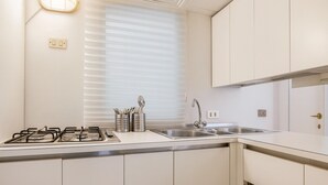 Une cuisine moderne équipée d’une cuisinière à gaz, d’un évier en acier inoxydable et de meubles blancs.