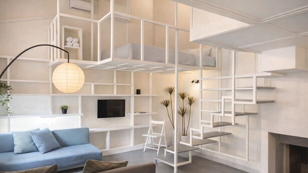 Un salon moderne avec un canapé bleu, un meuble de rangement blanc pour les appareils électroniques et un escalier agrémenté d’une cheminée.
