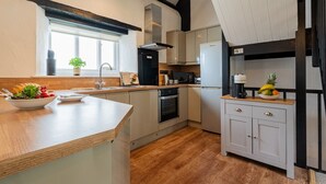 Een moderne keuken met een houten aanrecht, een ingebouwde oven, een koffieapparaat en een fruitschaal.