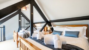 Een slaapkamer met een houten bed, een donker houten hoofdbord, een schuine plafond en een zichtbaar raam.