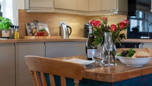 A dining table with a vase of flowers, a wine bottle, and a bowl of salad. - Bligh - cosy cottage near Crackington Haven (Cornwall)