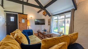 A cozy living room with a wooden ceiling, a television, and a view of the outdoors. - Bligh - cosy cottage near Crackington Haven (Cornwall)
