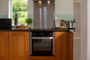 A kitchen with wooden cabinets, a stainless steel range hood, a microwave, and an oven.