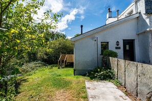 Ein modernes Haus mit weißer Fassade, einer Holzdielen-Terrasse und einem Betonweg, der zum Eingang führt.