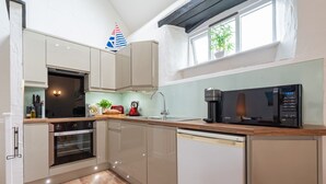 A modern kitchen with a built-in oven, microwave, and dishwasher. - Butterwell - Treworgie Barton Cottages (Cornwall)
