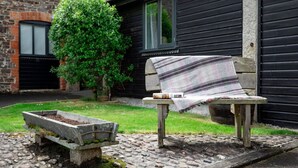 Un espace extérieur aménagé dans un style rustique, avec un banc et un petit jardinier.