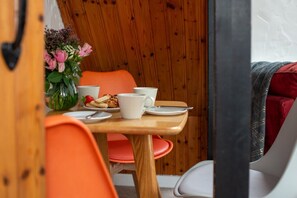 Comedor con una mesa de madera, sillas anaranjadas y un jarrón de flores.