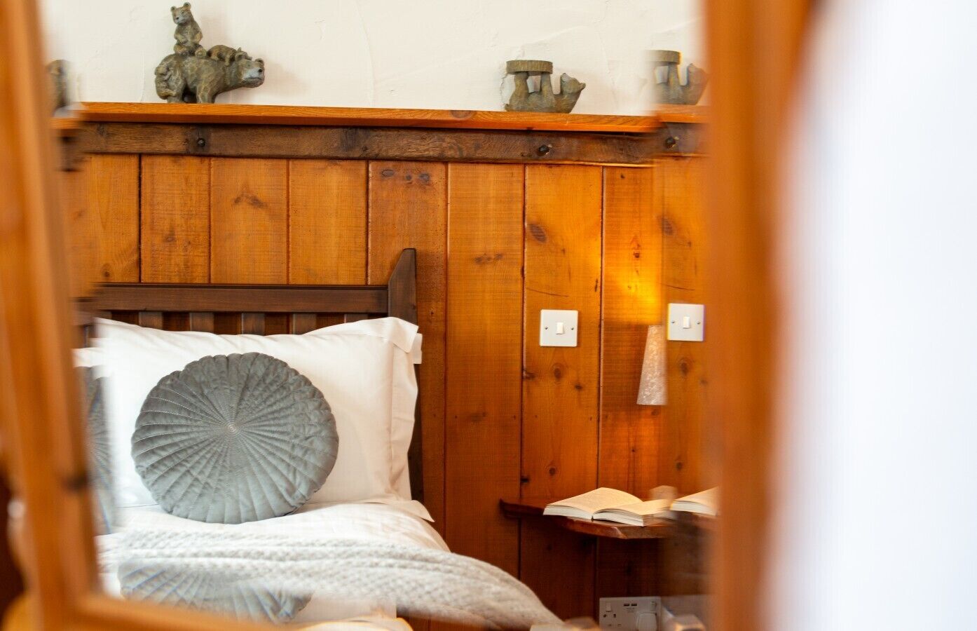 A wooden bed with a headboard, a pillow, and a bedside table with an open book.